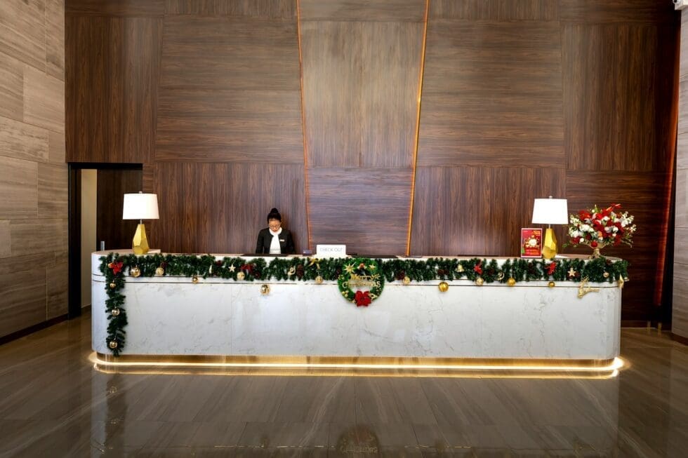 hotel-reception-desk-with-christmas-garland-decorations-hmg-plus Professional hotel front desk staff member at a luxury hotel reception decorated for the holidays in New York or Chicago