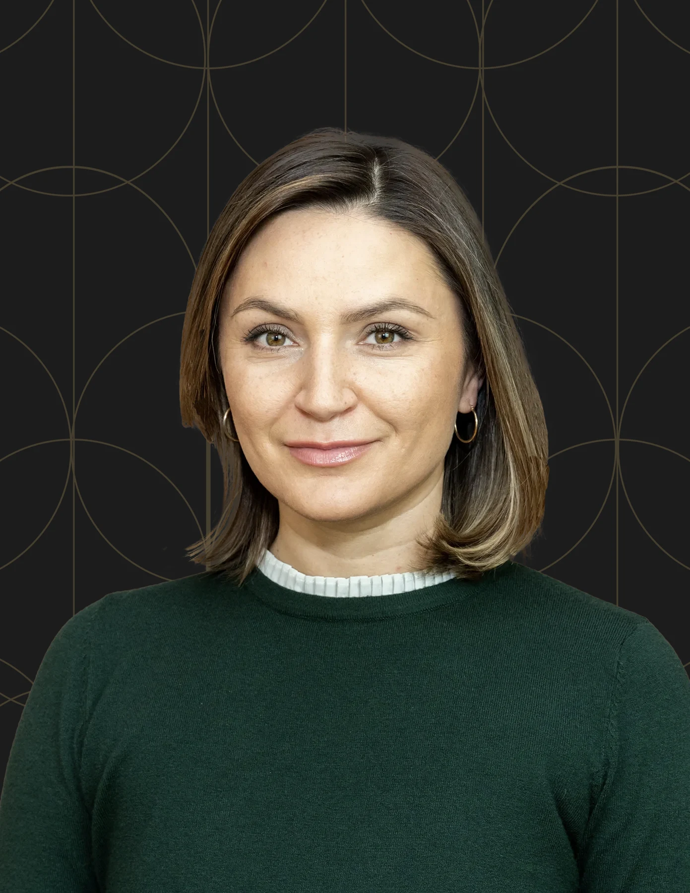 Professional headshot of a woman with a dark brown bob wearing a forest green sweater.