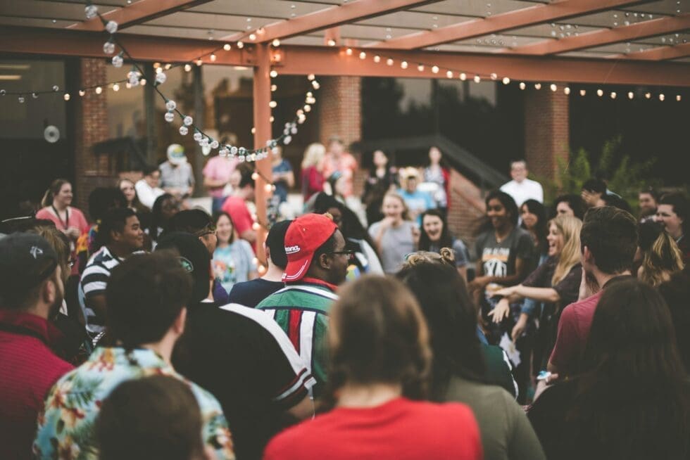 Large crowd of guests enjoying an outdoor private event with string lights at a professionally staffed social gathering
