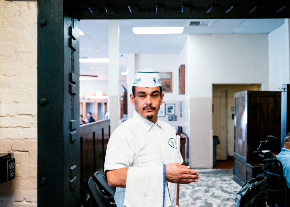 Professional catering staff member in uniform greeting guests at the entrance of an upscale restaurant or private event venue