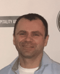 Smiling man in a light blue shirt photographed at a hospitality event