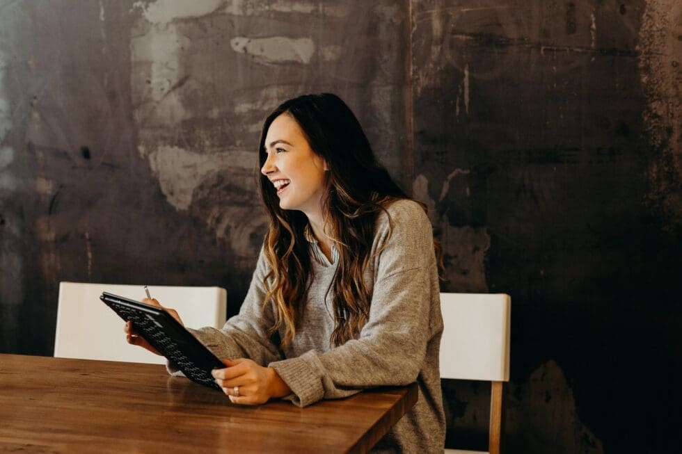Smiling hospitality professional holding a tablet during a staffing recruitment consultation with HMG+ in New York